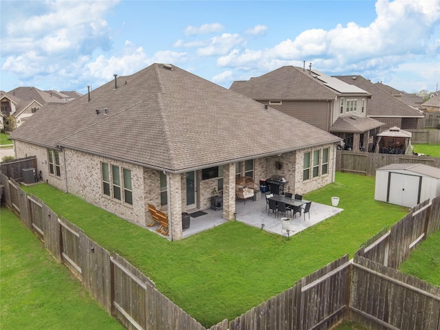 rear view of property featuring an outbuilding, a patio, a fireplace, roof with shingles, and a storage unit