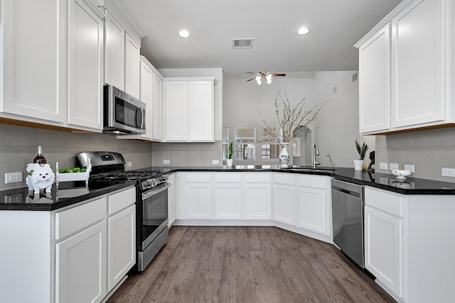 kitchen with a peninsula, appliances with stainless steel finishes, visible vents, and white cabinets