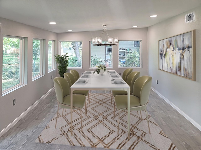 dining area with visible vents, light wood finished floors, baseboards, and an inviting chandelier