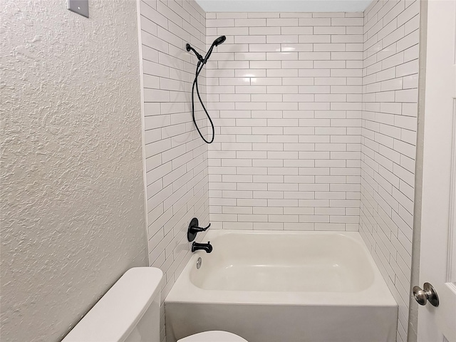 bathroom featuring shower / washtub combination, a textured wall, and toilet