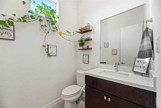 bathroom featuring toilet, vanity, and baseboards