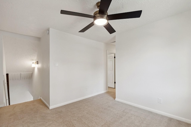 unfurnished room with baseboards, a textured ceiling, and light colored carpet