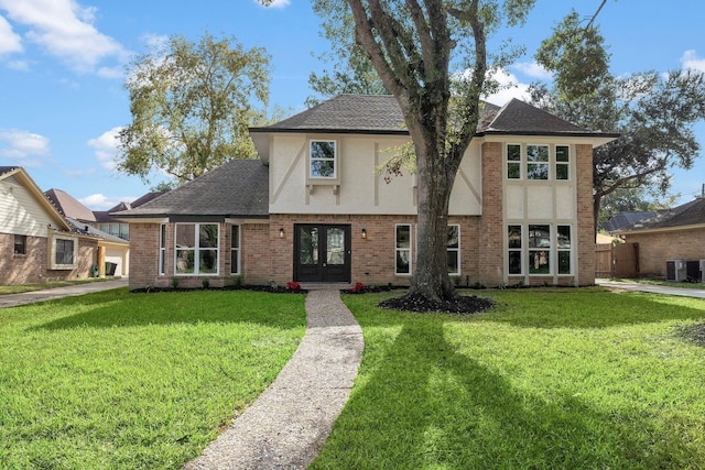 tudor-style house with a front yard, french doors, and central AC