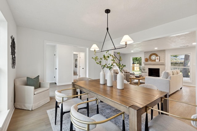 dining area with recessed lighting, a brick fireplace, a chandelier, light wood-type flooring, and baseboards