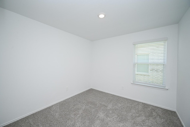 unfurnished room featuring carpet and baseboards