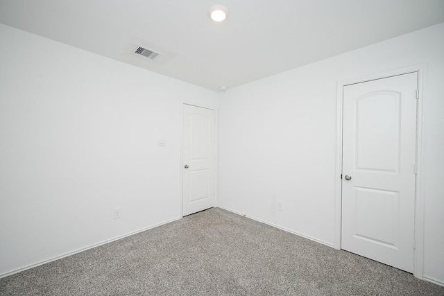 carpeted empty room with visible vents and baseboards