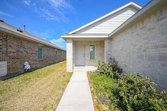 entrance to property featuring brick siding and a yard