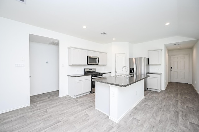 kitchen featuring visible vents, dark countertops, light wood-style flooring, appliances with stainless steel finishes, and a sink