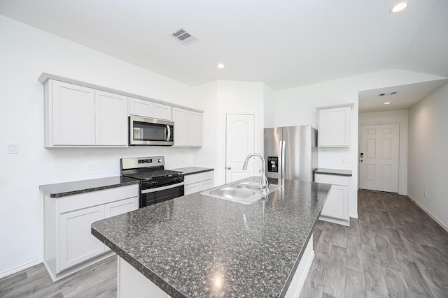 kitchen featuring light wood finished floors, stainless steel appliances, visible vents, a kitchen island with sink, and a sink