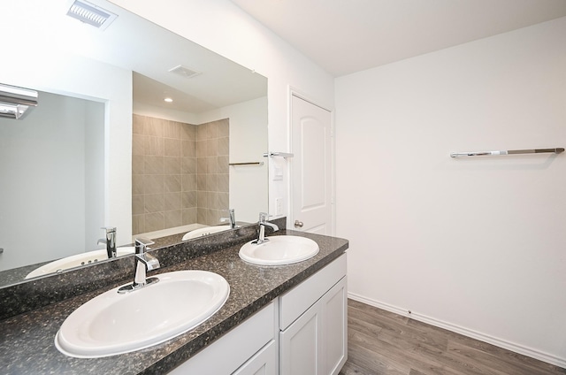 bathroom with double vanity, wood finished floors, a sink, and visible vents