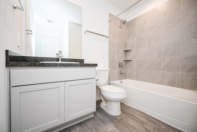 full bath with visible vents, toilet, vanity, shower / tub combination, and wood finished floors