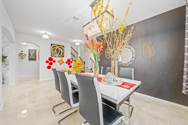 dining room featuring baseboards, visible vents, arched walkways, an inviting chandelier, and stairs