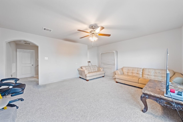 living room with arched walkways, carpet flooring, visible vents, baseboards, and a ceiling fan