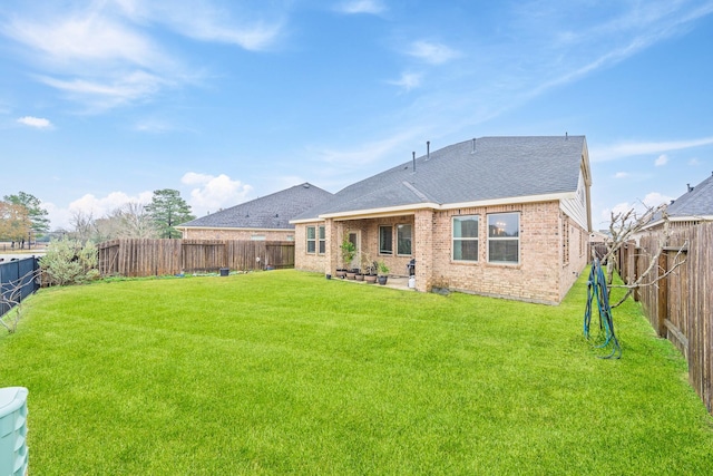 back of house featuring a yard, brick siding, and a fenced backyard