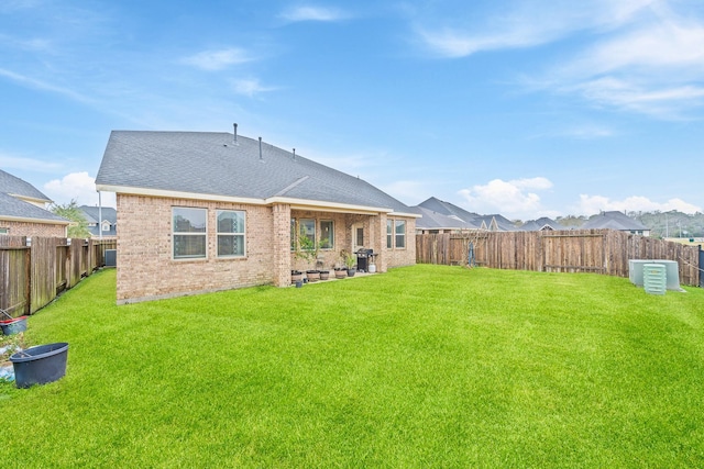 rear view of property with brick siding, a yard, and a fenced backyard