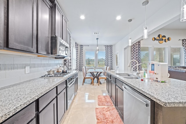 kitchen featuring light tile patterned floors, tasteful backsplash, appliances with stainless steel finishes, open floor plan, and a sink