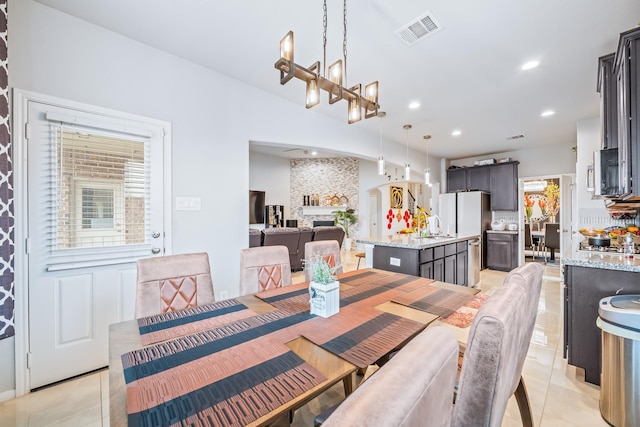 dining space featuring light tile patterned floors, recessed lighting, visible vents, an inviting chandelier, and a large fireplace