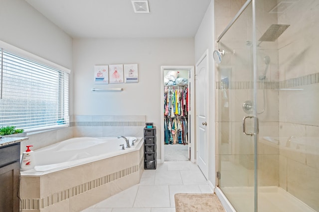 full bathroom featuring tile patterned flooring, visible vents, a shower stall, a bath, and a walk in closet