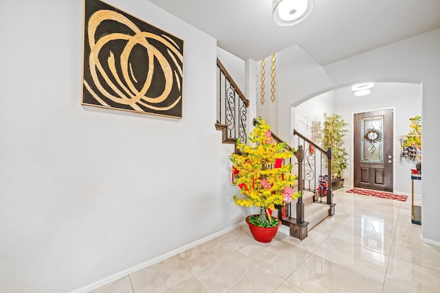 entryway featuring arched walkways, baseboards, and stairs