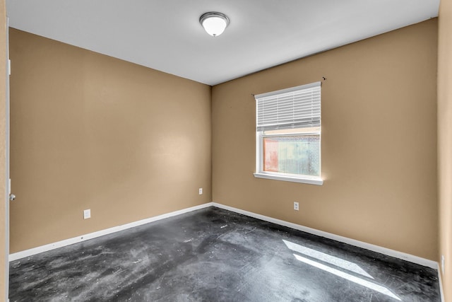 spare room with concrete flooring and baseboards