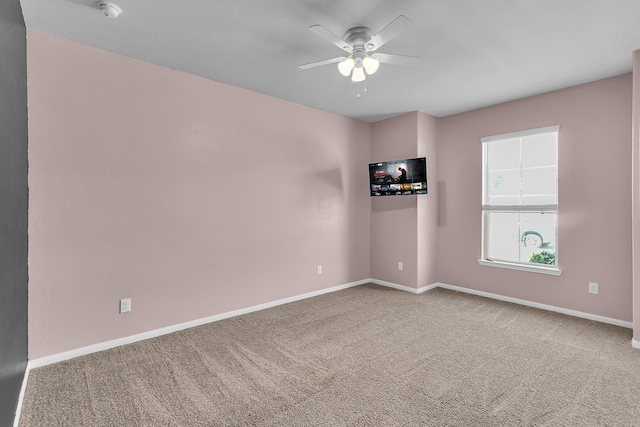 carpeted empty room with ceiling fan and baseboards