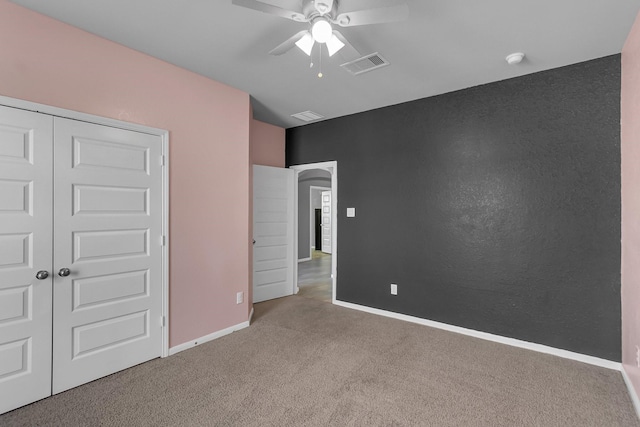 unfurnished bedroom featuring baseboards, visible vents, a ceiling fan, carpet flooring, and a closet