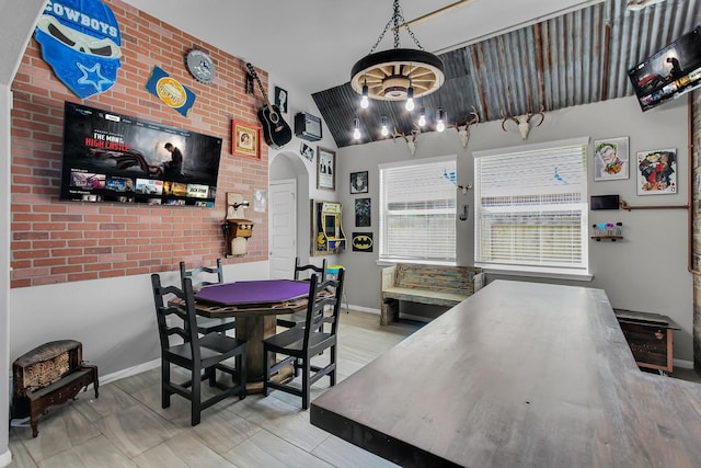 dining room featuring arched walkways, brick wall, wood finished floors, and baseboards