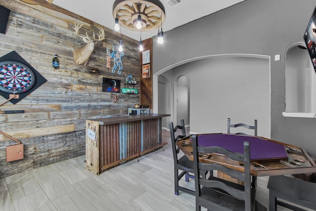 bar featuring wood walls, visible vents, an accent wall, and arched walkways