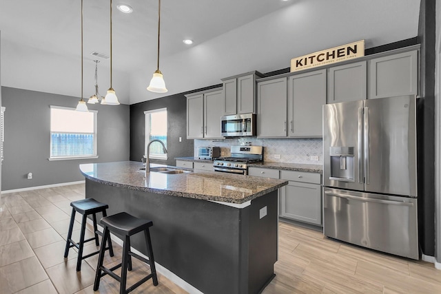 kitchen featuring appliances with stainless steel finishes, backsplash, a sink, and gray cabinetry