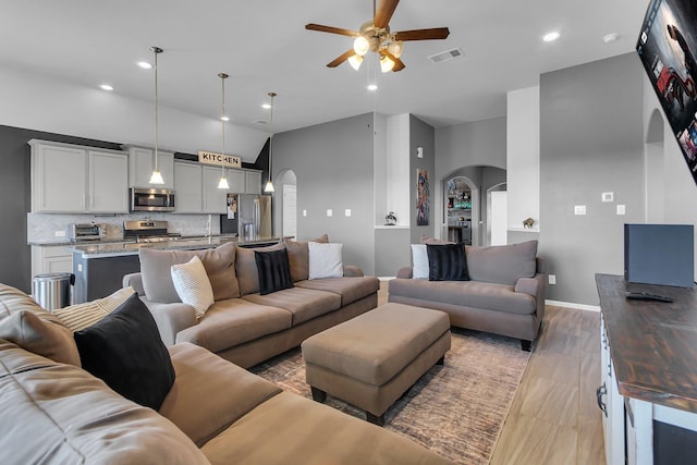 living area with light wood finished floors, a toaster, visible vents, arched walkways, and ceiling fan