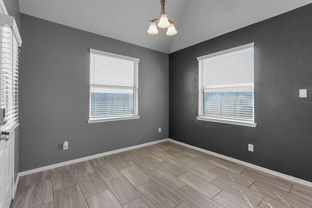 empty room with a chandelier, lofted ceiling, and baseboards