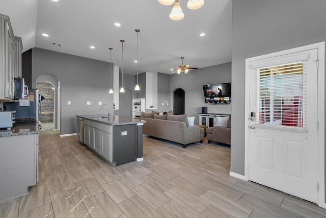 kitchen with gray cabinets, arched walkways, stainless steel appliances, and a sink