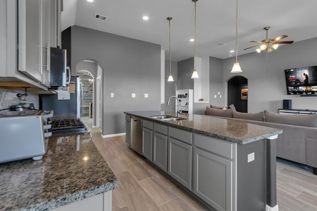 kitchen featuring arched walkways, a sink, dishwasher, and gray cabinetry