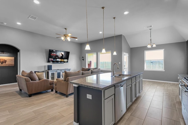 kitchen featuring arched walkways, visible vents, dark stone counters, stainless steel appliances, and a sink