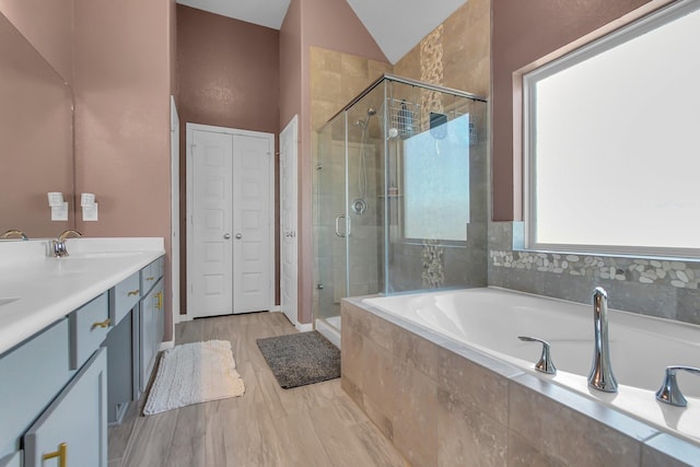 bathroom featuring lofted ceiling, wood finished floors, vanity, a shower stall, and a bath