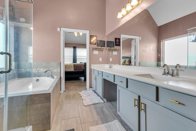 full bathroom featuring a sink, tiled tub, double vanity, and connected bathroom