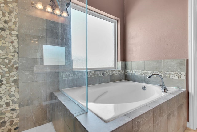 full bathroom featuring a textured wall and a garden tub