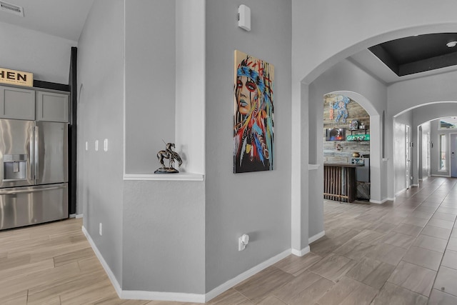 corridor featuring arched walkways, visible vents, and baseboards