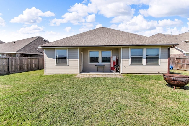 rear view of property featuring roof with shingles, a lawn, a patio area, and a fenced backyard