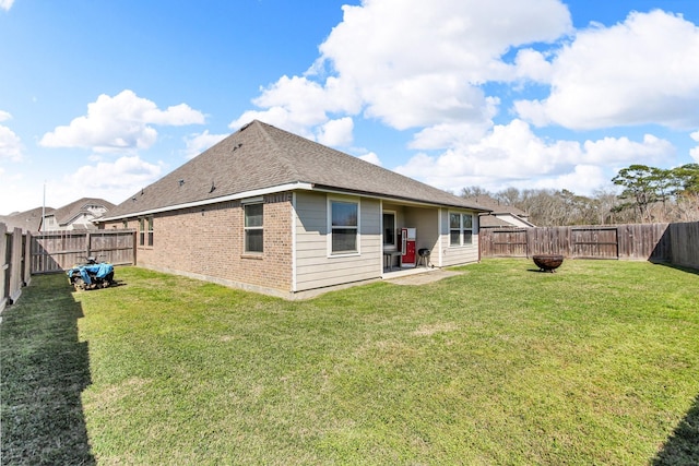 rear view of house with a yard, a fenced backyard, and brick siding