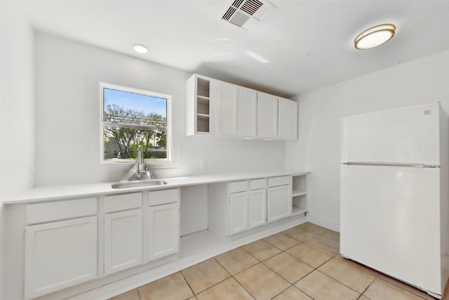 2430 5th Ave N, Texas City, TX 77590 - kitchen featuring visible vents, light countertops, freestanding refrigerator, white cabinets, and a sink