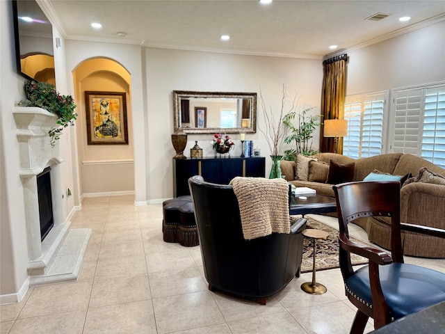 living room featuring a fireplace with raised hearth, ornamental molding, and light tile patterned floors