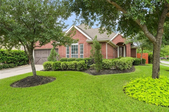 view of front of property with driveway, roof with shingles, an attached garage, a front lawn, and brick siding