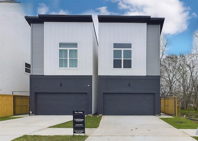 view of front of home with a garage, driveway, fence, and board and batten siding