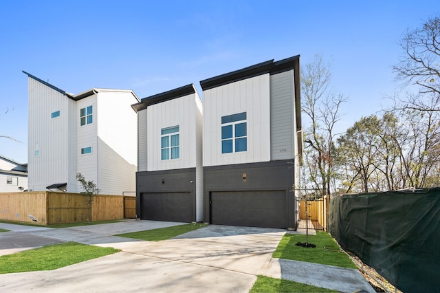 view of front of house featuring a garage, board and batten siding, fence, and concrete driveway