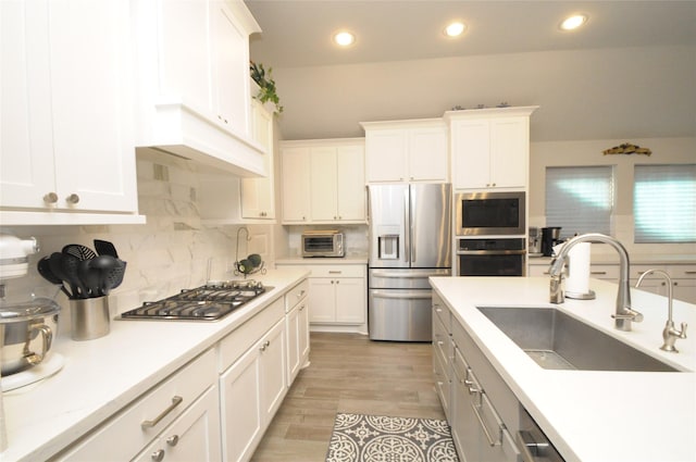 kitchen featuring a sink, white cabinetry, light countertops, appliances with stainless steel finishes, and tasteful backsplash