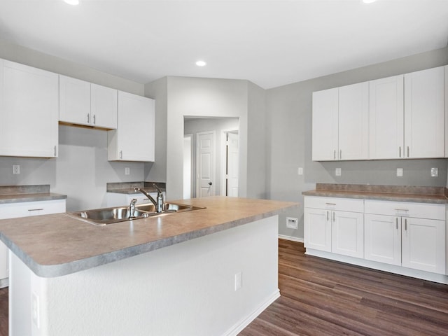 kitchen with dark wood-type flooring, a sink, white cabinetry, baseboards, and an island with sink