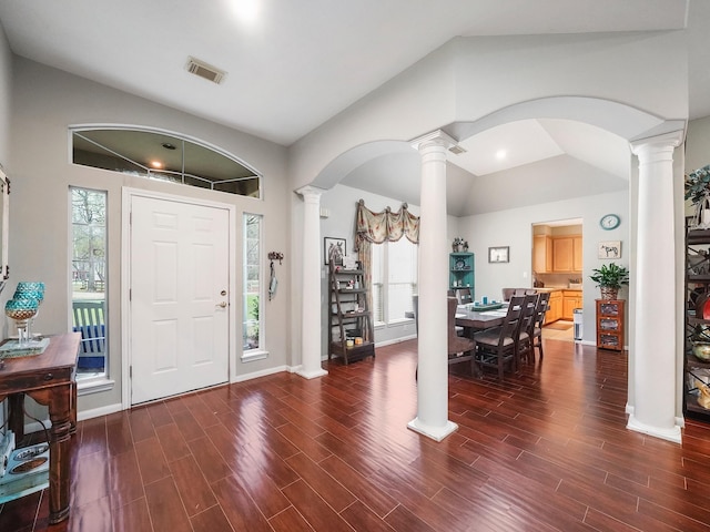 foyer with dark wood-style floors, decorative columns, arched walkways, and vaulted ceiling