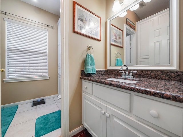 bathroom with toilet, visible vents, baseboards, vanity, and tile patterned floors