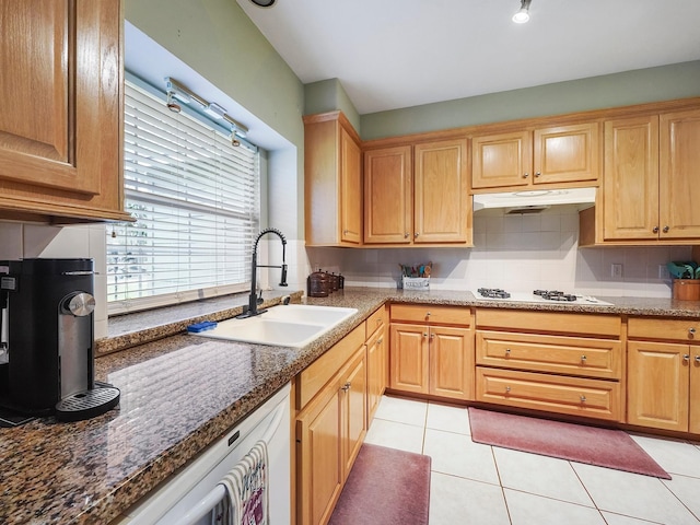 kitchen featuring light tile patterned floors, white appliances, a sink, under cabinet range hood, and backsplash